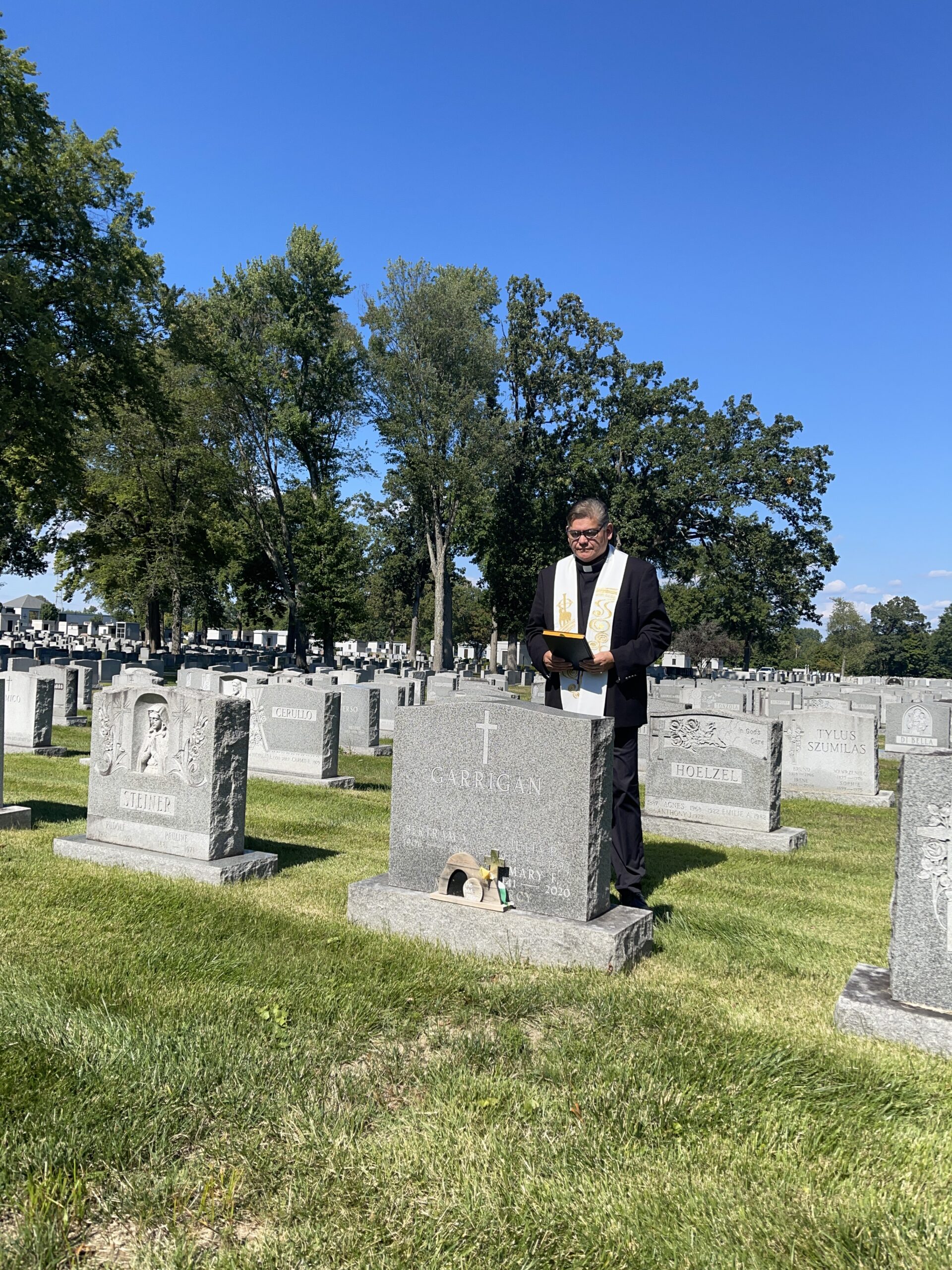 Father Joe prays at grave at Gate of Heaven Cemetery